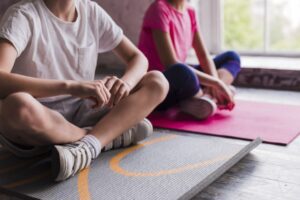 close up of boy and girl sitting on grey and pink exercise mat Pequeno